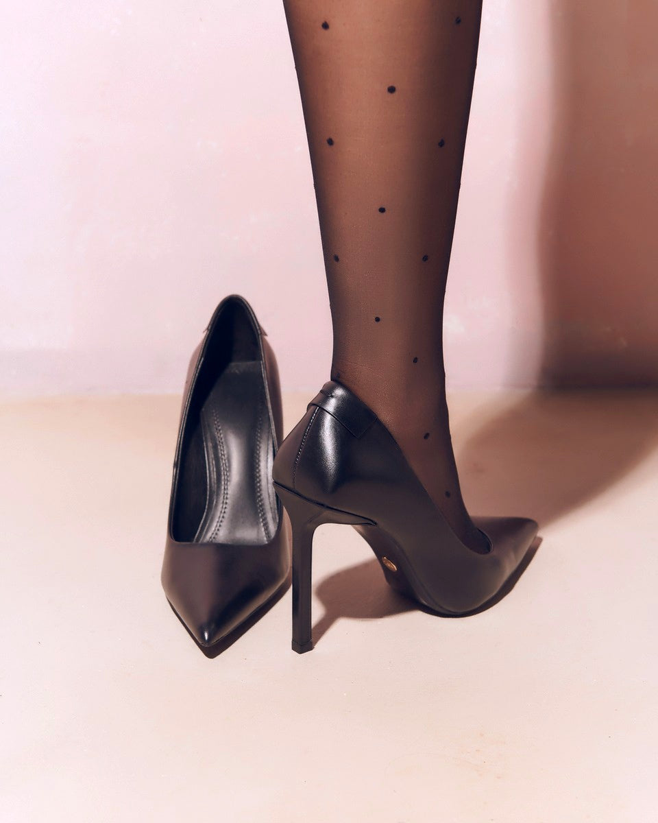 kobiece nogi w czarnych rajstopach w kropki i buty na wysokim obcasie typu szpilki