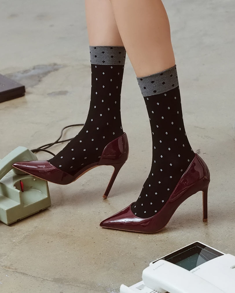 Modelka prezentująca czarne damskie skarpetki rajstopowe do szpilek ozdobione wzorem w kropki Gabriella Dina